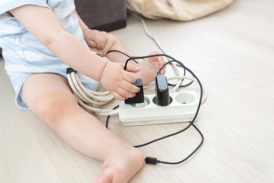  	dziecko wyciągające kable z przedłużacza elektrycznego